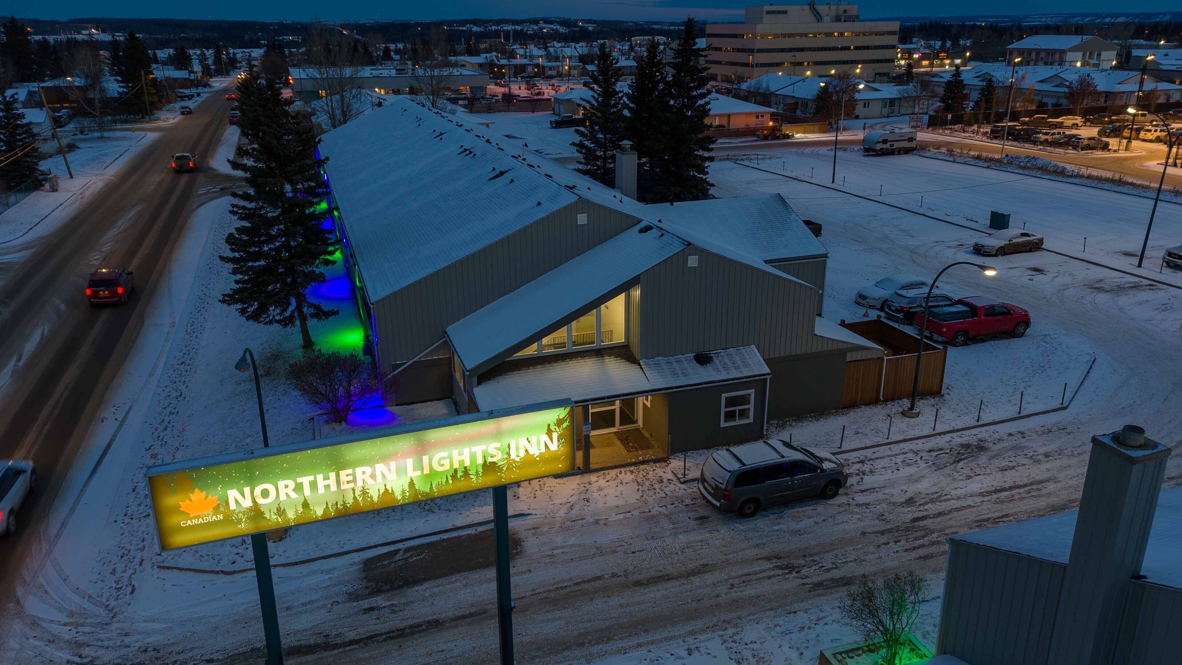 Un hotel con un gran letrero iluminado que anuncia "Northern Lights Inn" y un estacionamiento cubierto de nieve.
