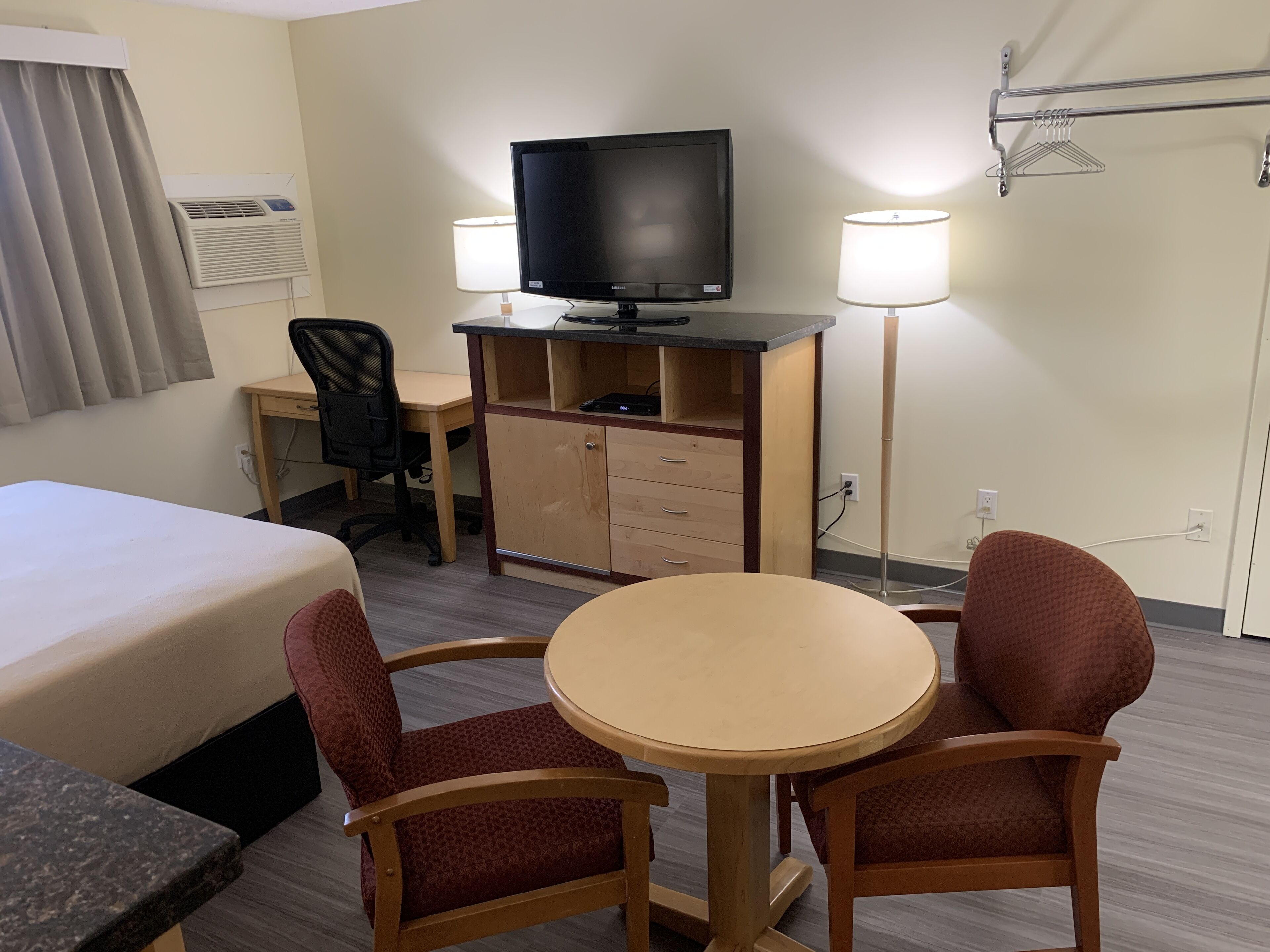 A hotel room with a bed, desk, chair, television, and two lamps.