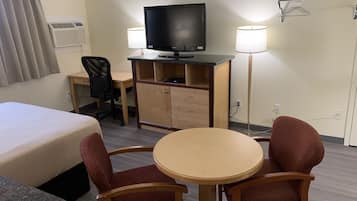 A hotel room with a bed, desk, chair, television, and two lamps.