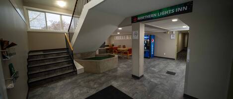 A hotel lobby with a staircase, a coffee table, and a Pepsi vending machine.