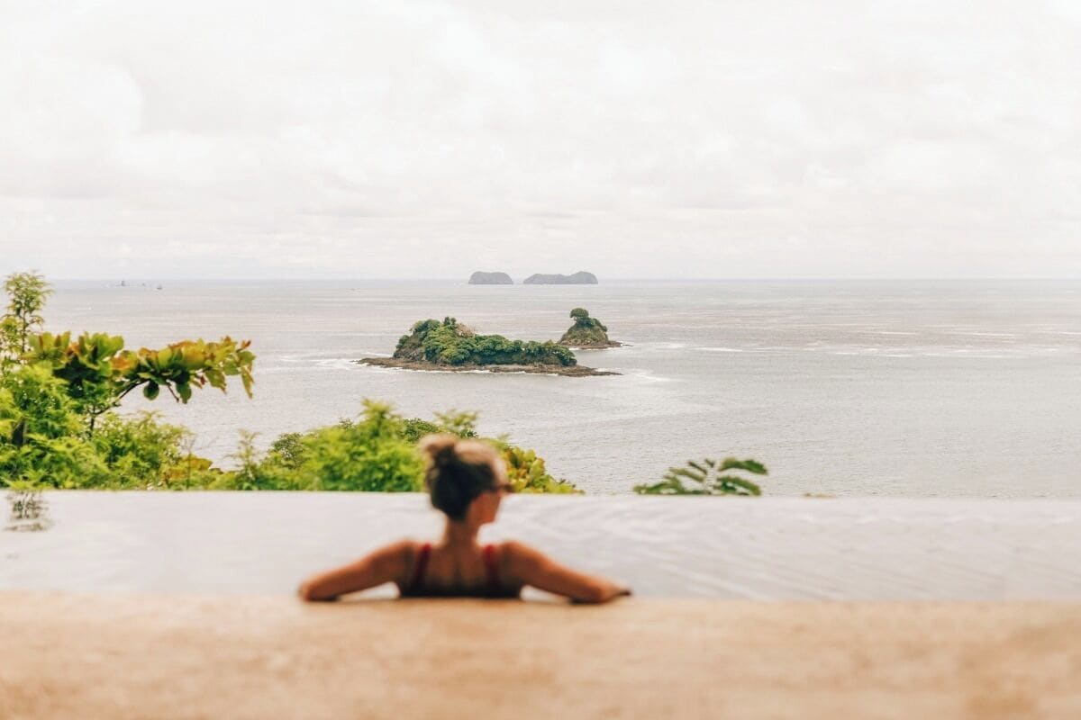 A person sitting on a balcony overlooking a body of water with islands in the distance.