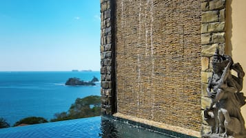 A stone wall with a water feature, a view of the ocean, and a statue.