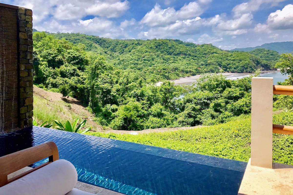 Una piscina con vistas a un exuberante valle verde y un río.