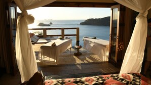 A room with a view of the sea, featuring two tables with white tablecloths and a small decorative bowl on a pedestal. - Casa Chameleon Hotel Las Catalinas - Adults Only (Tempate)