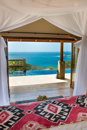 A room with a view of the ocean, a patterned rug, and a statue. - Casa Chameleon Hotel Las Catalinas - Adults Only (Tempate)