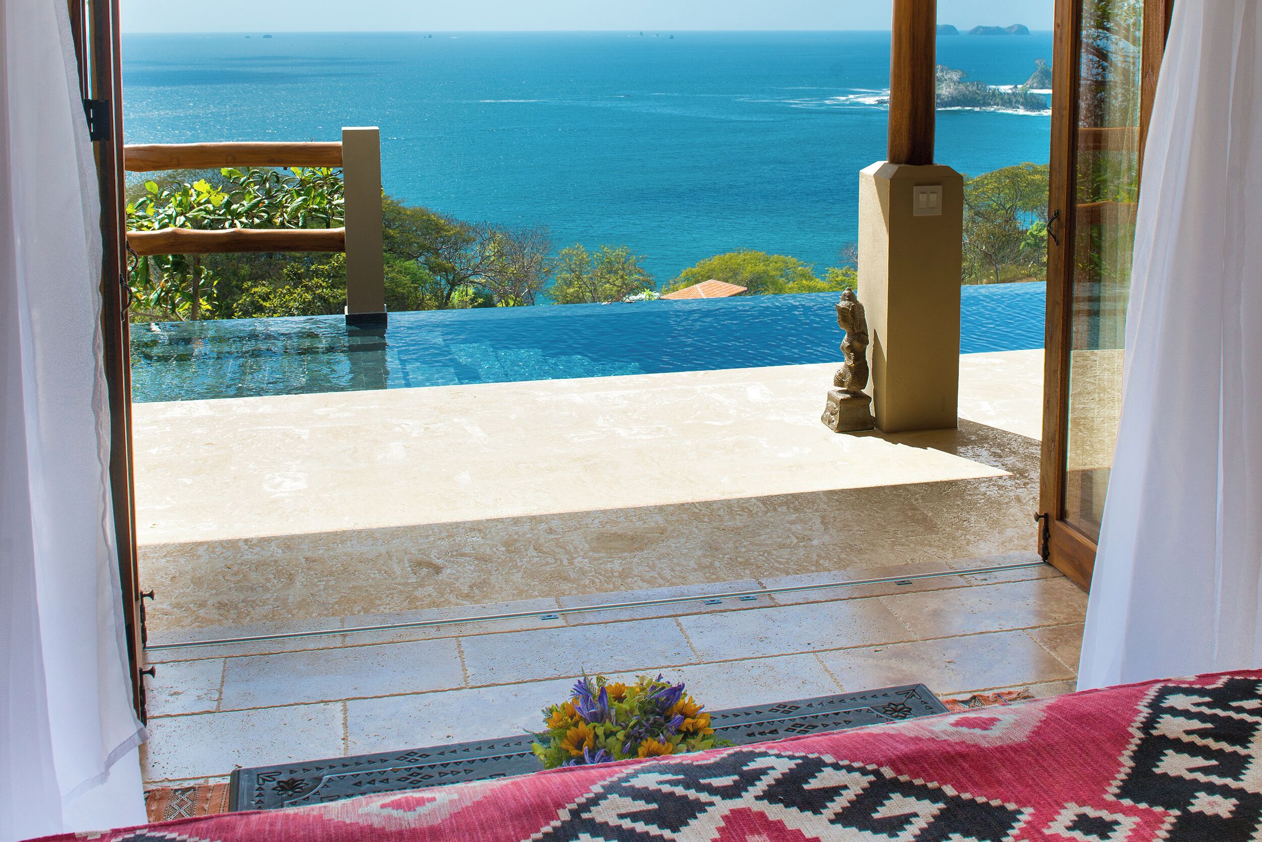 A view from a balcony with an infinity pool overlooking the ocean.