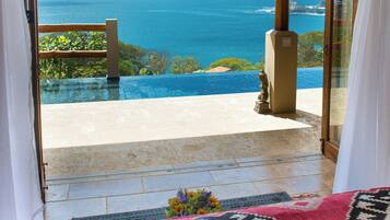A view from a balcony with an infinity pool overlooking the ocean.