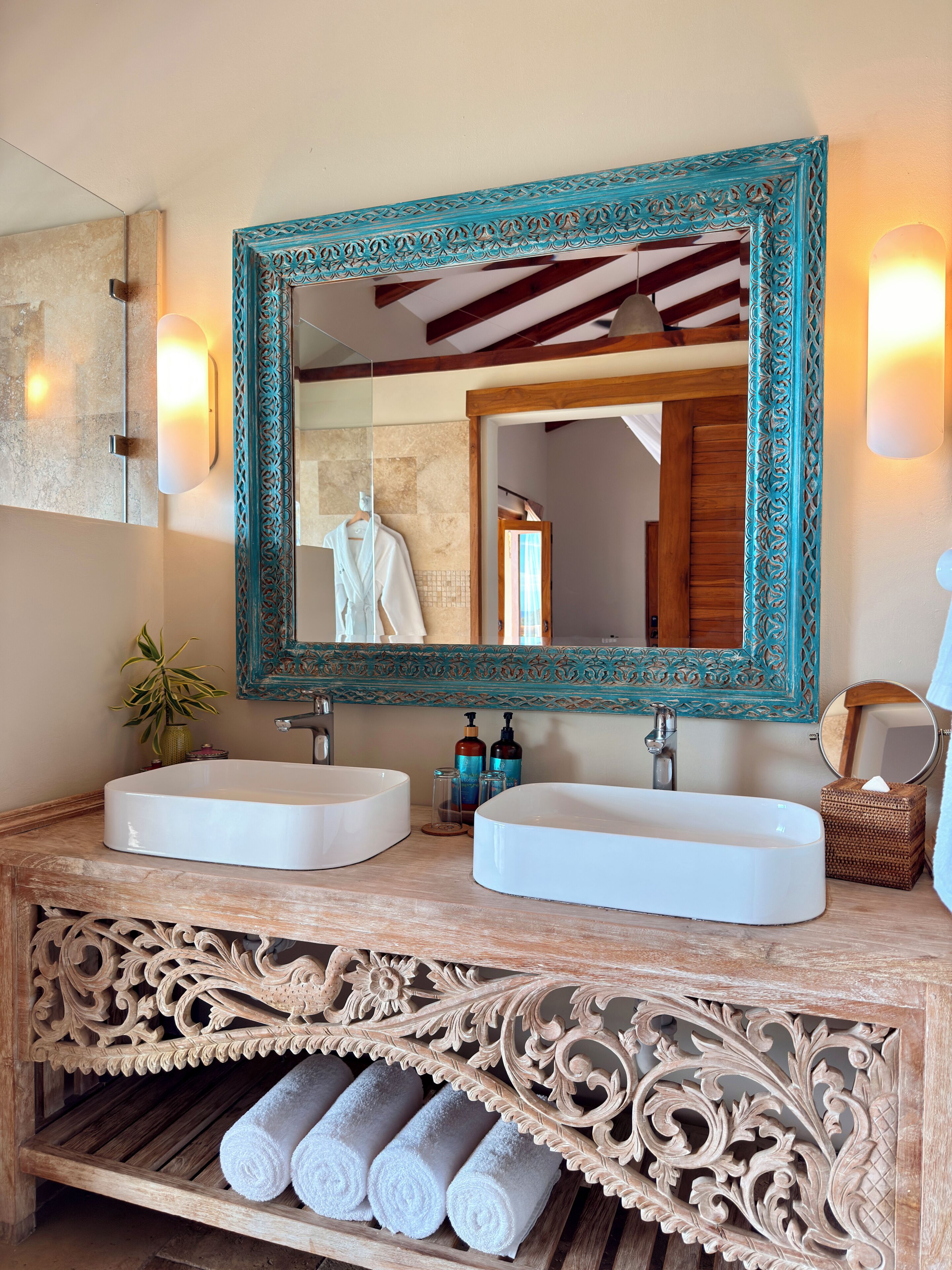 A bathroom with two sinks, a large mirror, and a decorative wooden vanity.