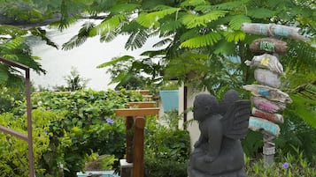 Un jardín con una estatua de piedra de un ángel sosteniendo un cartel con varios nombres.