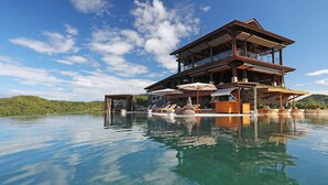 A multi-story building with a pool, outdoor seating, and a view of the surrounding landscape.