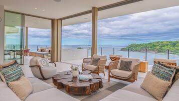 A spacious balcony with a view of the sea and a lush green landscape.