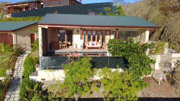 A modern house with a swimming pool, a covered patio, and a view of a hillside.
