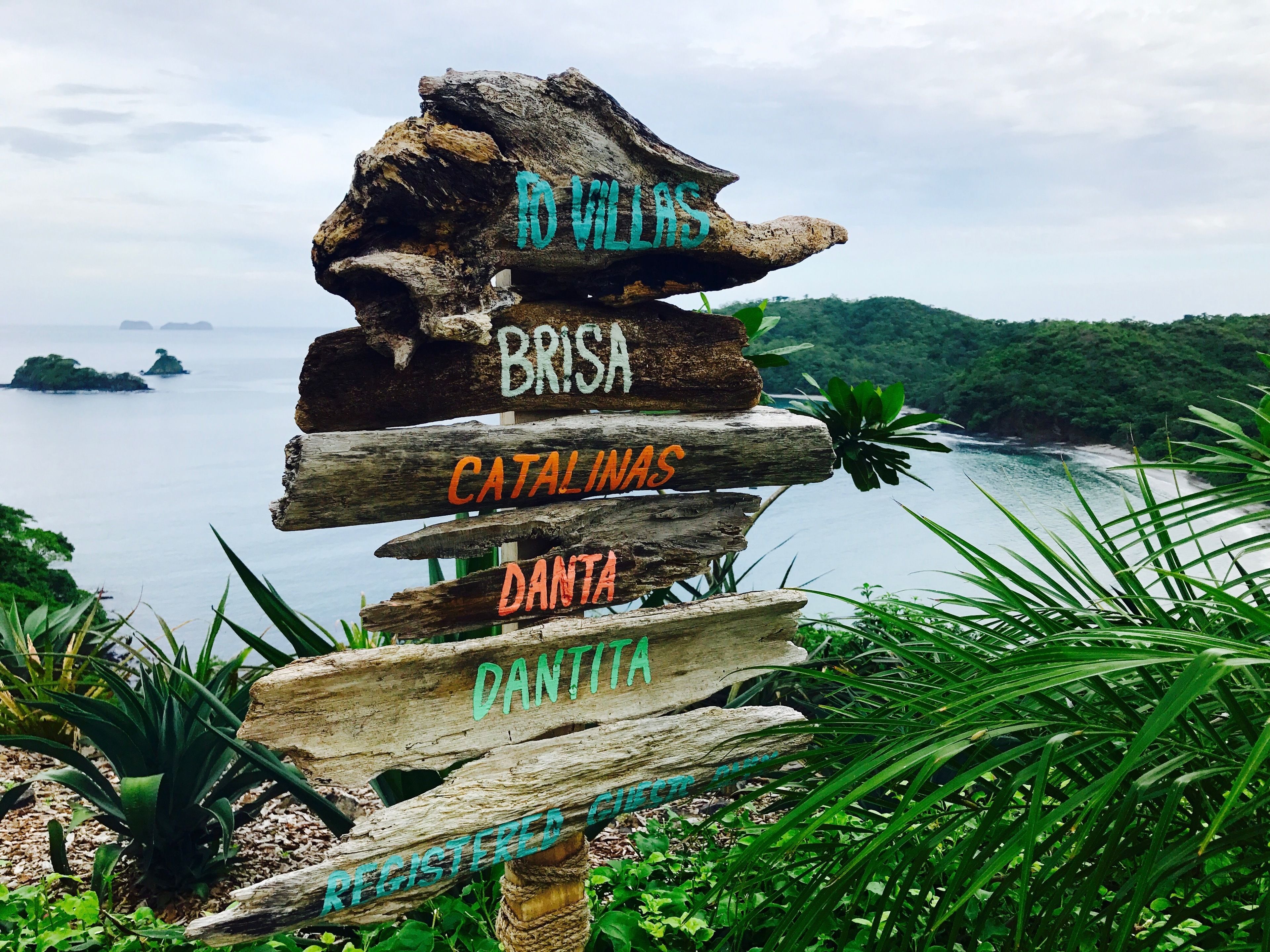 Un panneau indicateur en bois, avec les destinations indiquées à l’aide de couleurs différentes.