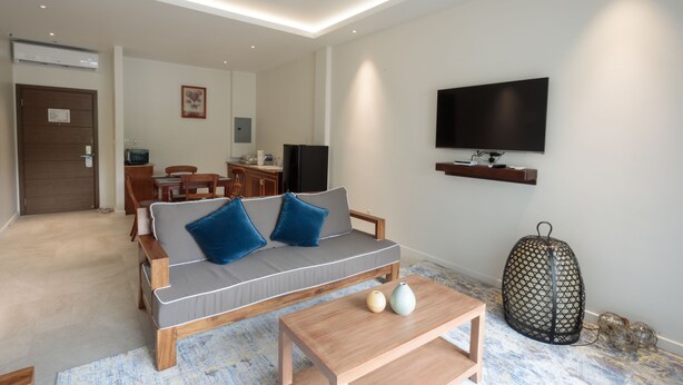 A modern living room with a sofa, coffee table, and TV. - Cove Resort Palau (Malakal Island)