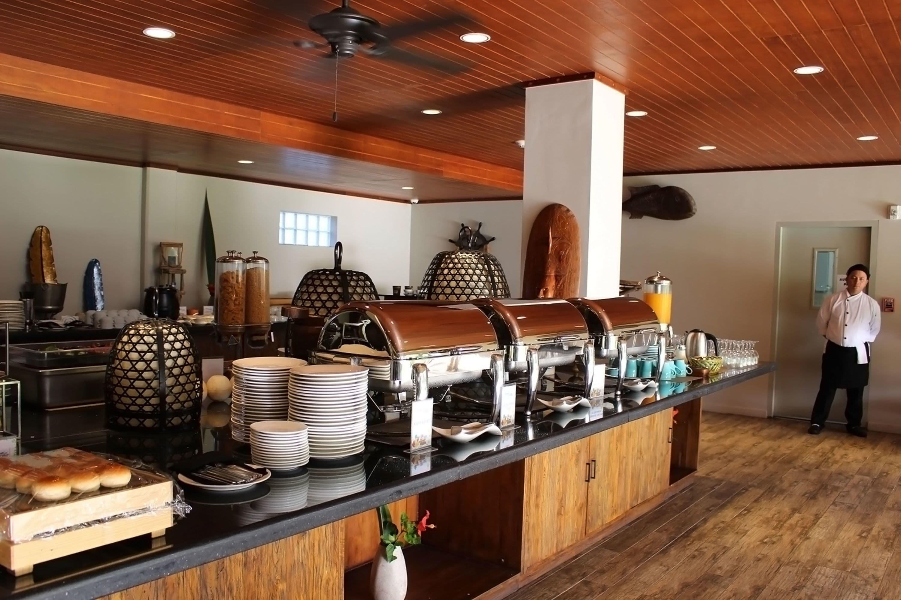 Uma mesa de buffet com várias estações de comida, incluindo uma churrasqueira, um espaço para bebidas e uma variedade de pratos expostos em um balcão.
