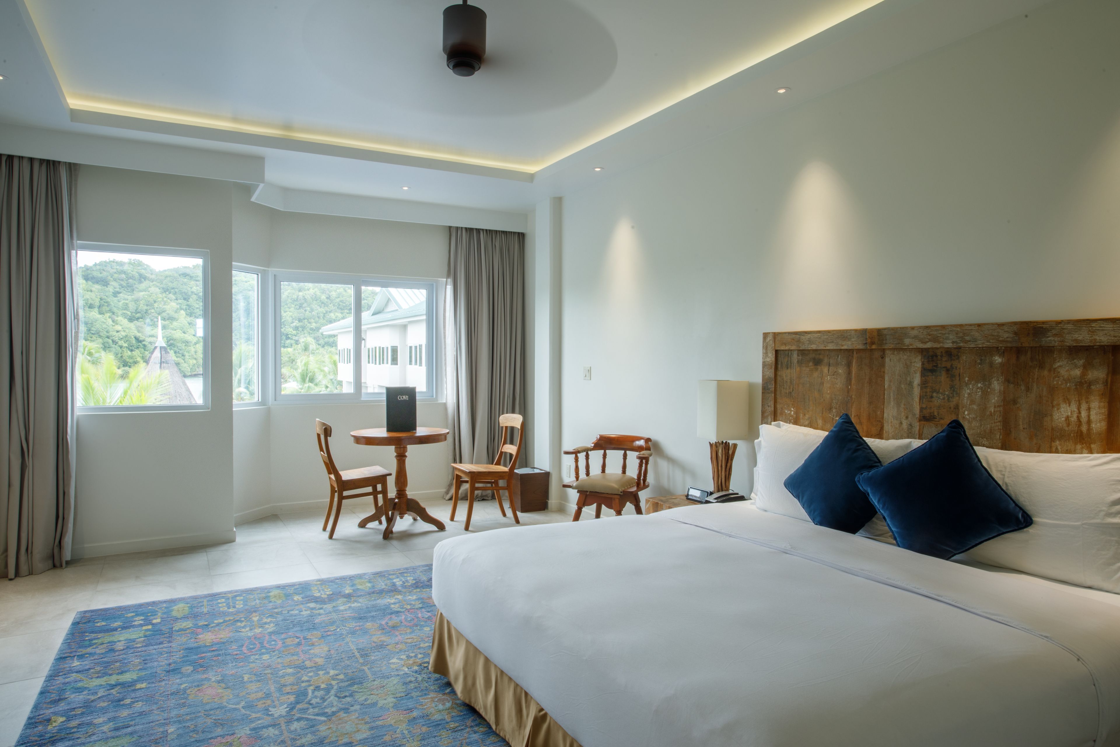 Habitación de hotel con una cama grande, un escritorio, dos sillas, una mesita y vistas a zonas verdes.
