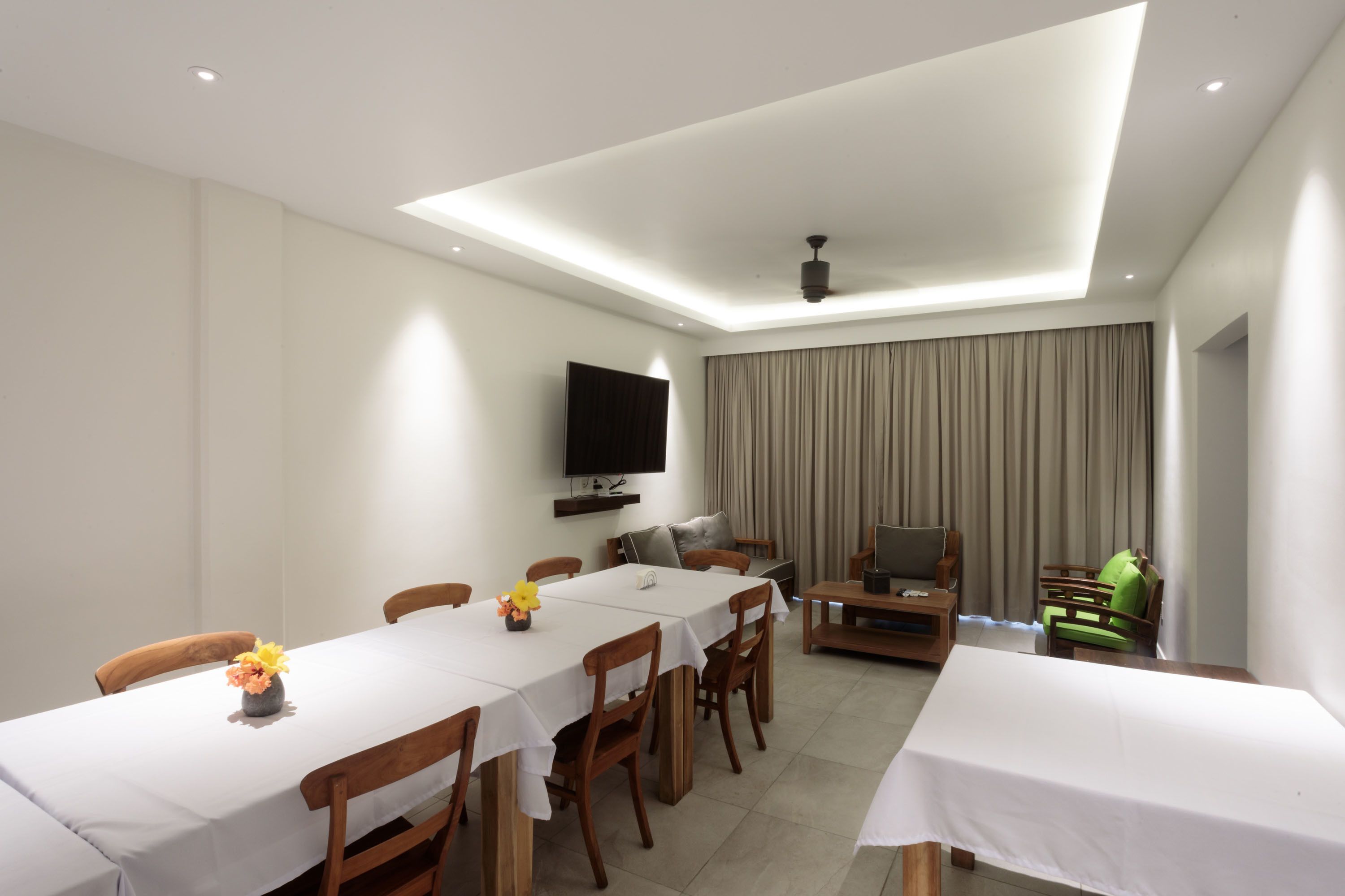 Un comedor con una mesa larga, sillas, un televisor de pantalla plana y un sofá.