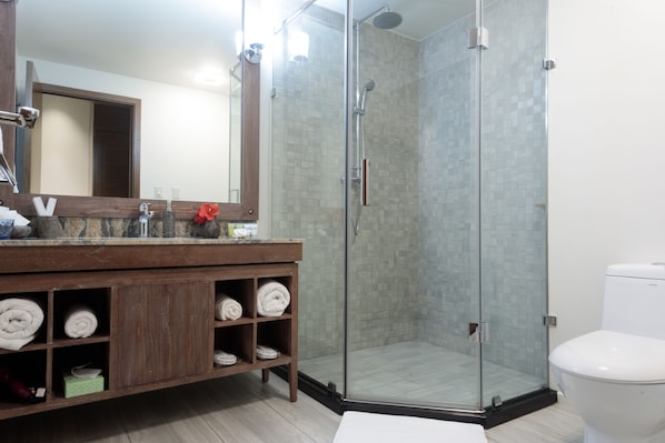 A modern bathroom with a glass-enclosed shower, a wooden vanity with towels, and a white toilet. - Cove Resort Palau (Malakal Island)