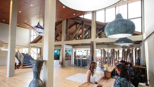 A spacious lobby with high ceilings, a staircase, and a large hanging light fixture. - Cove Resort Palau (Malakal Island)