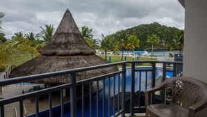 A pool area with a thatched-roof structure, a chair, and a view of a mountainous landscape. - Cove Resort Palau (Malakal Island)