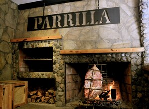 A stone fireplace with a hanging sign that reads "PARRILLA".
