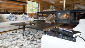 A modern living room with a fireplace, a sofa, a coffee table, and a book titled "The Road" by Cormac McCarthy. - Hotel Raudal (Palena)
