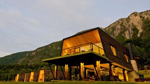 A modern building with a wooden exterior, a balcony, and a view of a mountainous landscape. - Hotel Raudal (Palena)
