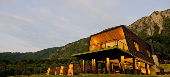 A modern building with a wooden exterior, a balcony, and a view of a mountainous landscape. - Hotel Raudal (Palena)