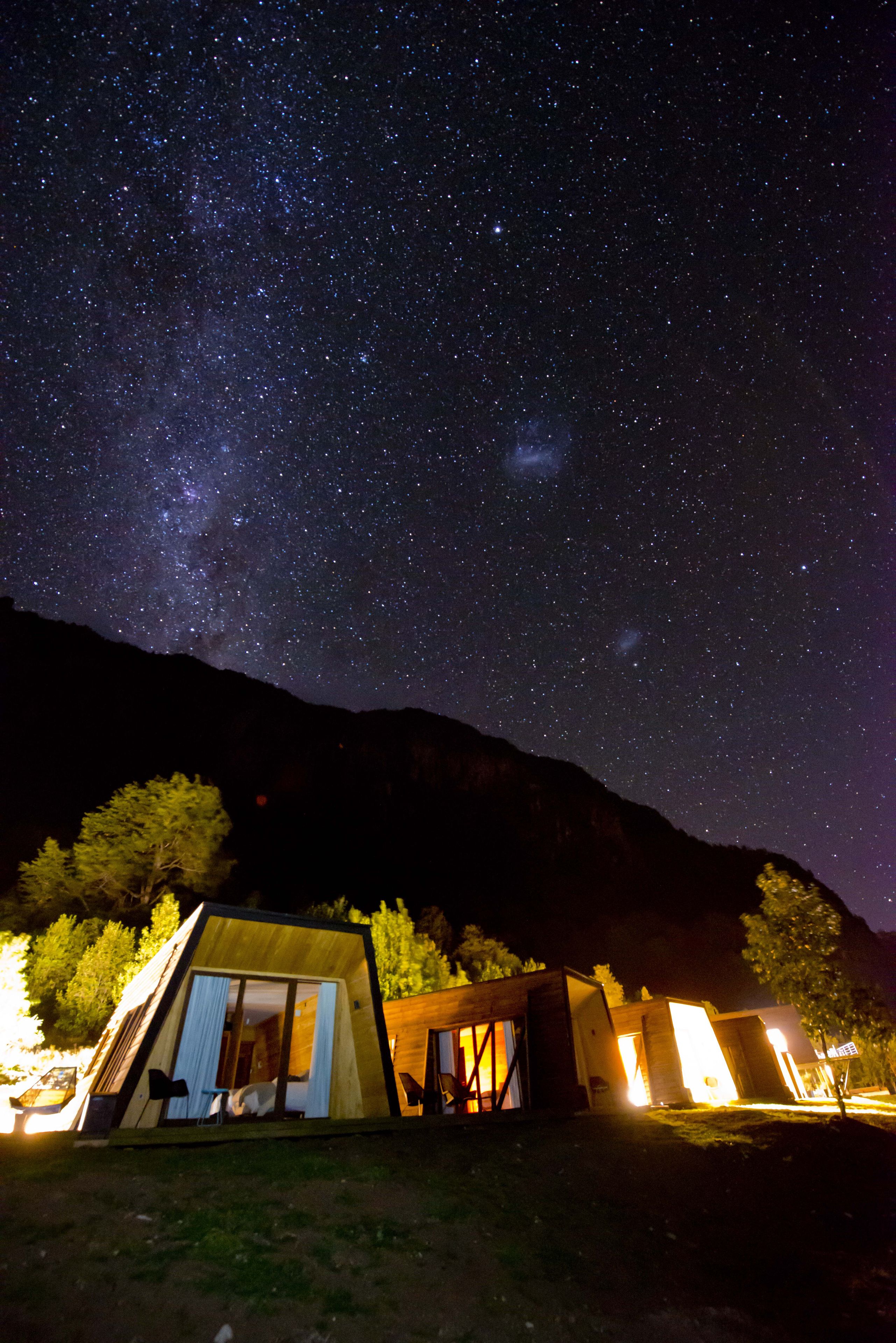 Cielo estrellado con una zona de alojamiento en tiendas de campaña.