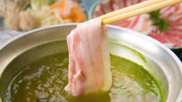 A hot pot with a piece of meat being held by chopsticks.