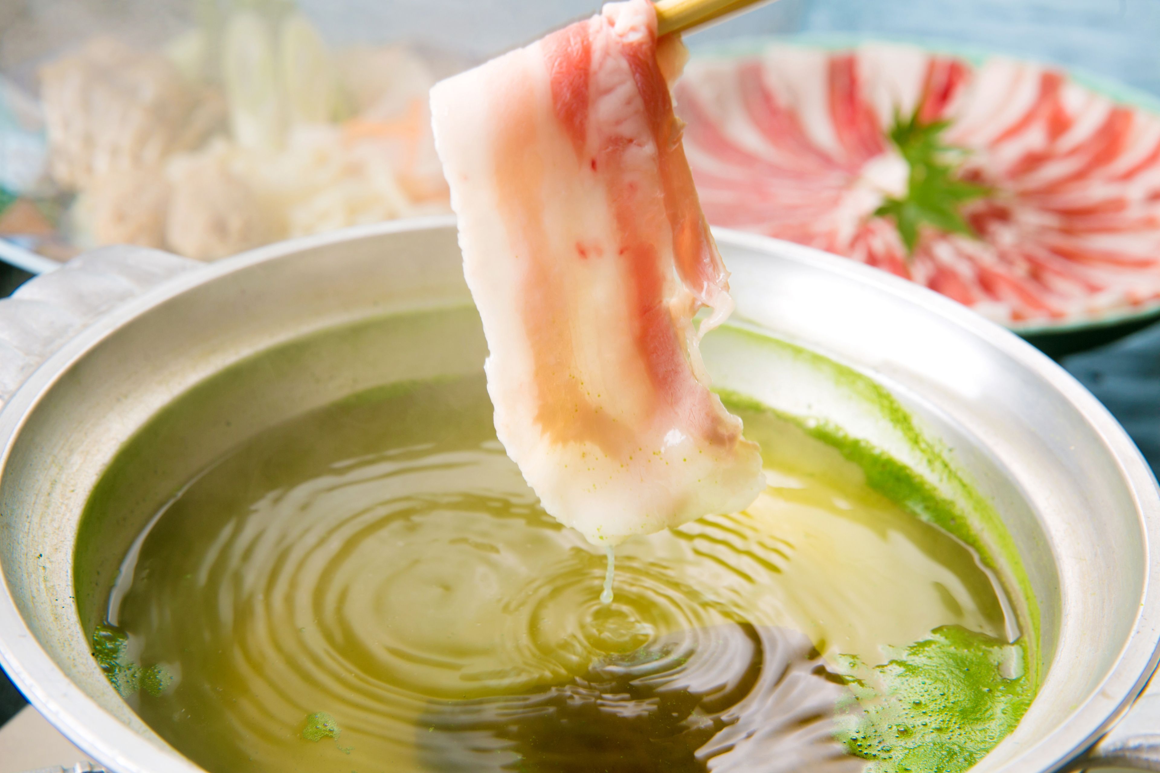 A bowl of soup with a piece of meat being lifted out.
