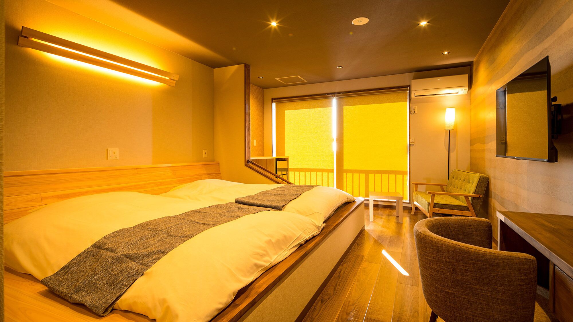 Ein Hotelzimmer mit Bett, Sessel, Schreibtisch, Balkon und Blick ins Freie.