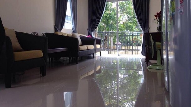 A living room with a sofa set, a glass door leading outside, and a refrigerator.