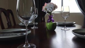 A dining table with empty wine glasses, plates, and a vase with flowers.