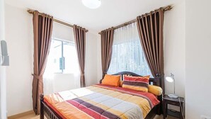 A bedroom with a bed, curtains, a bedside table, and a lamp.