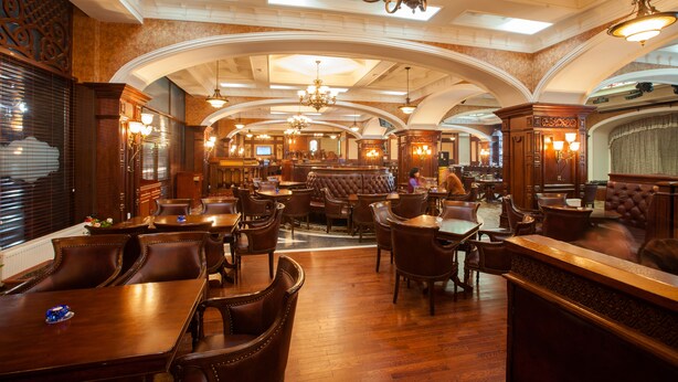 A spacious restaurant with high ceilings, arched alcoves, and multiple chandeliers.