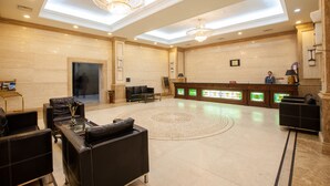 A spacious lobby with a reception desk, seating area, and decorative lighting.