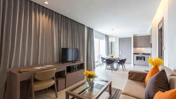 A modern living room with a flat-screen TV, a dining area, and a kitchen.