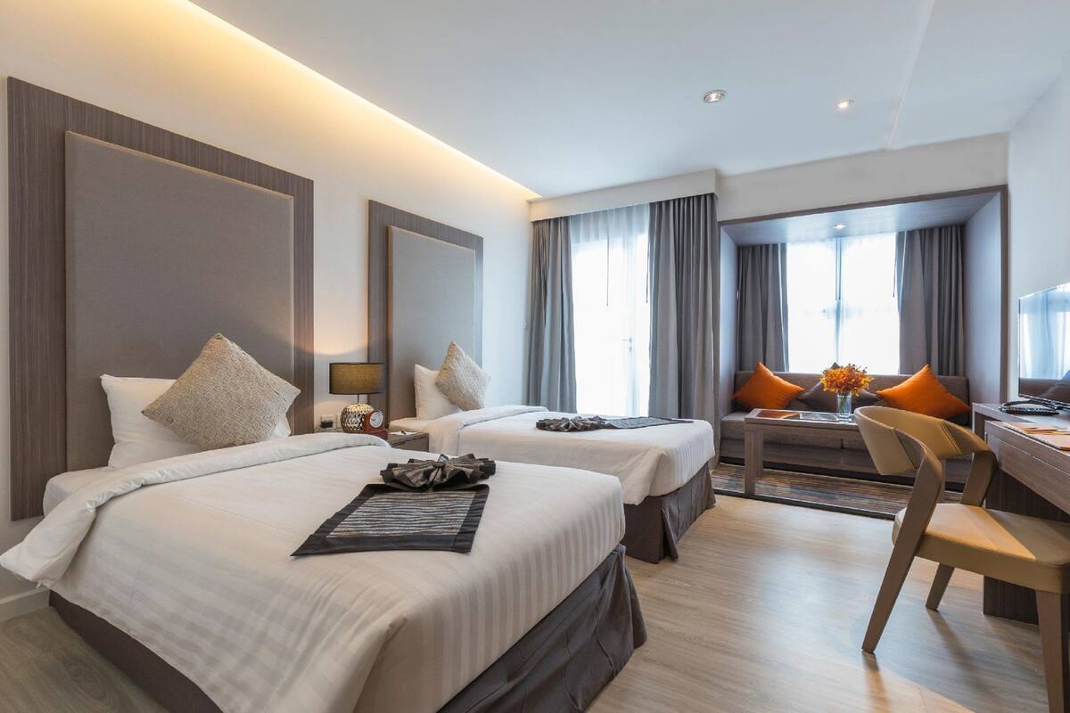 A hotel room with two beds, a desk, and a chair.