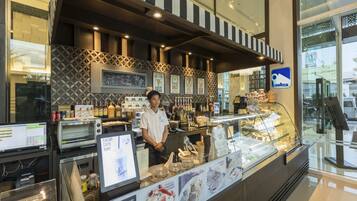 A coffee shop counter with a menu display, coffee machines, and a variety of beverages.