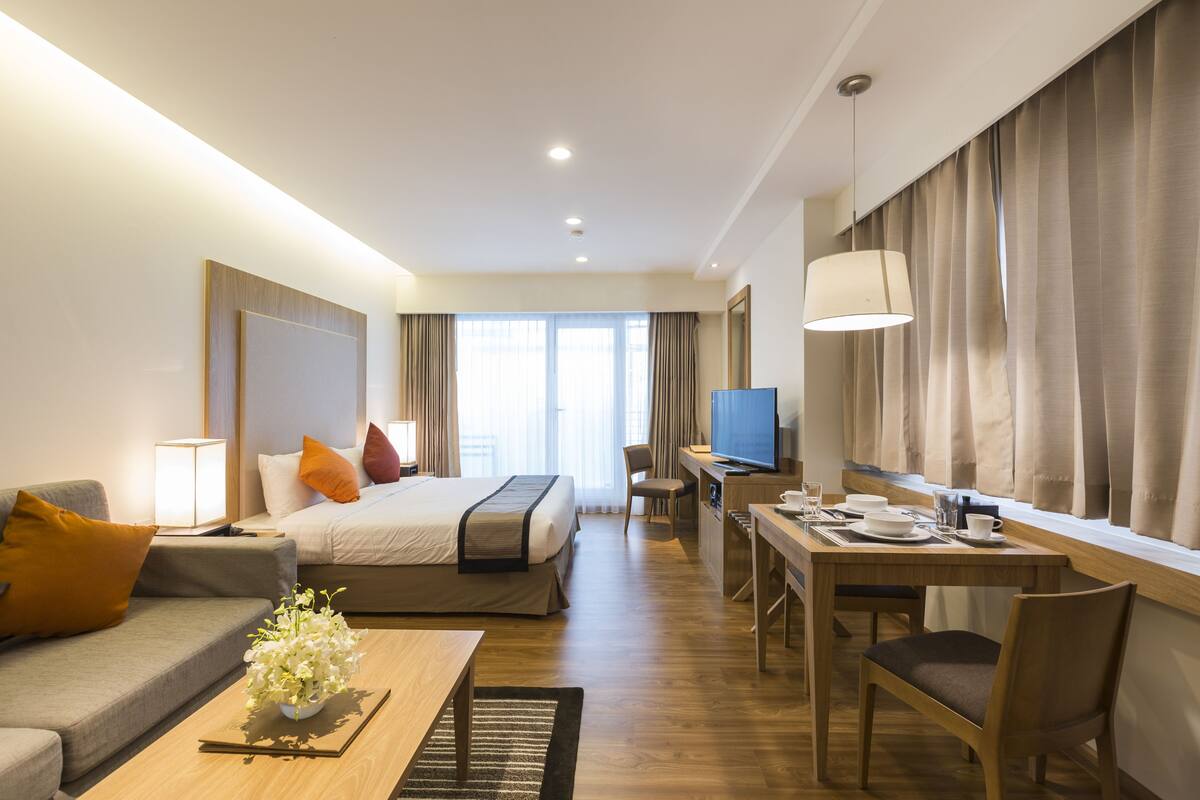 A hotel room with a bed, a desk, a television, and a sofa.