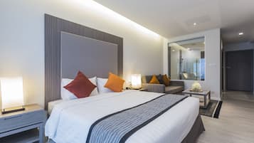 Une chambre d’hôtel moderne avec un grand lit, des tables de chevet, un canapé et un miroir.