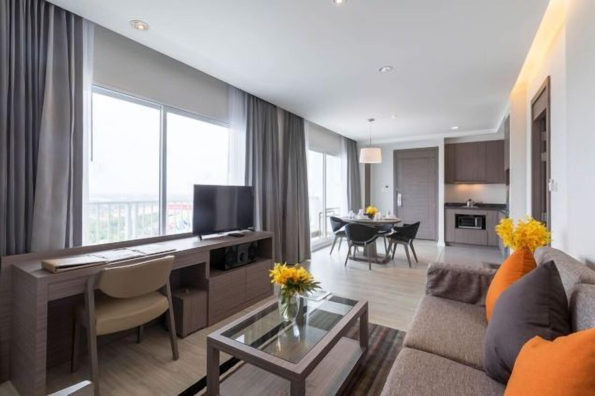 Una habitación de hotel moderna con escritorio, sofá, zona de comedor y cocina.