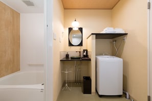 A small bathroom with a bathtub, a sink, a mirror, and a washing machine.