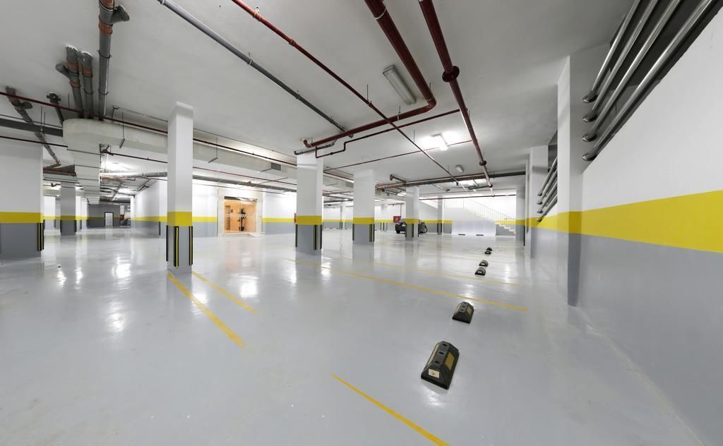 A spacious indoor parking garage with clear yellow lines marking parking spaces, a clean and well-lit environment, and visible structural columns.