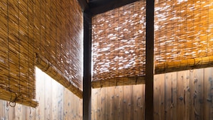 A traditional Japanese onsen with a wooden interior, a green ceramic hot spring tub, and a bamboo backdrop.