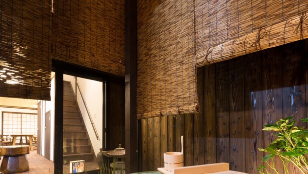 A traditional Japanese-style interior with a large wooden bathtub, a staircase, and a minimalist design.