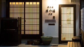 A traditional Japanese building with a wooden facade, a tiled roof, and a large window with a grid pattern.