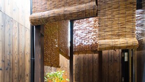 A traditional Japanese-style garden with a bamboo fence, a hot spring bath, and a small tree.