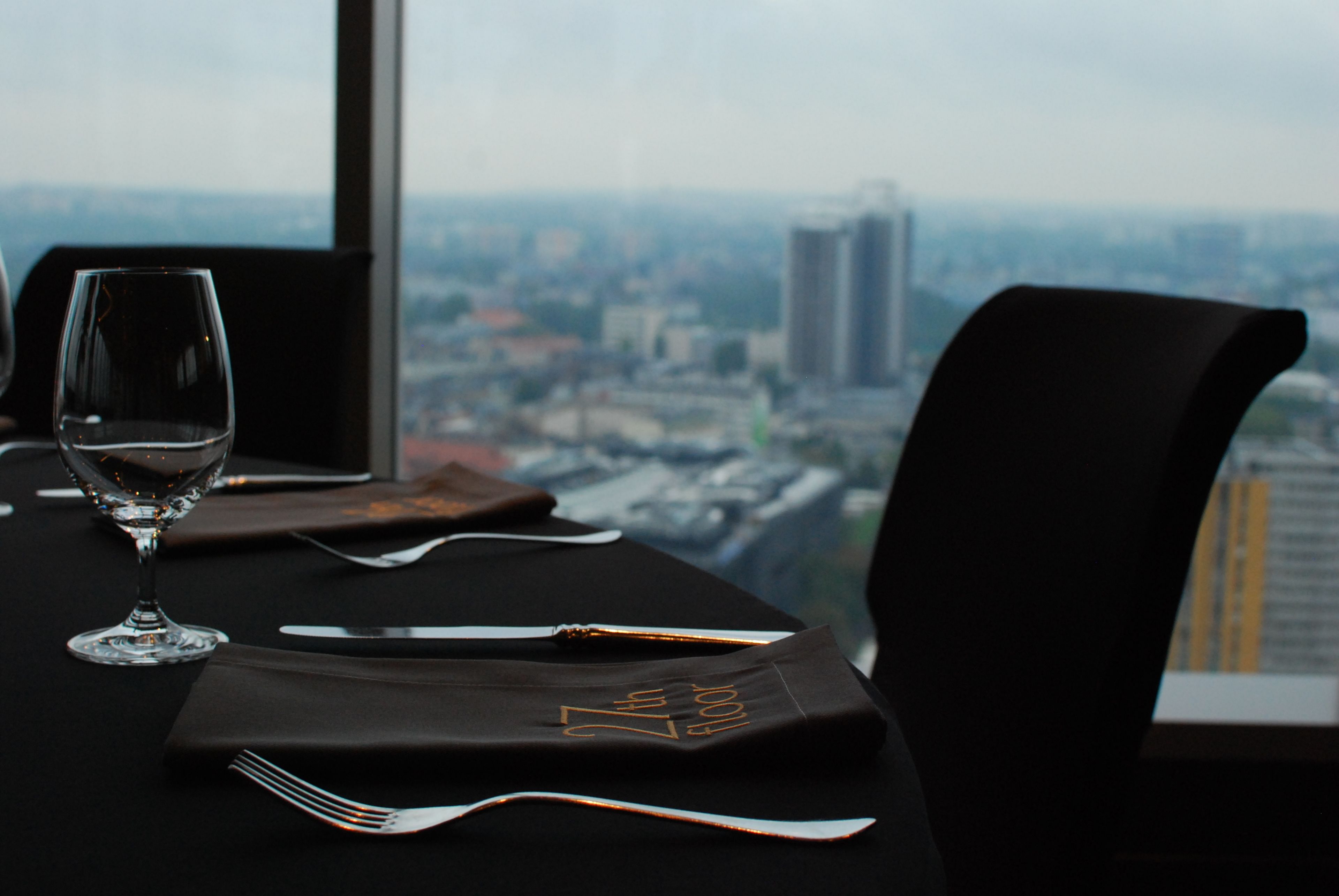 Una mesa de comedor dispuesta con una copa de vino, cubiertos y una servilleta con la inscripción '7th floor'.